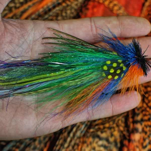 Urban Fly Co. vibrant multicolored feathered fishing lure held in hand, showcasing detailed design with blue, green, yellow, and orange accents.