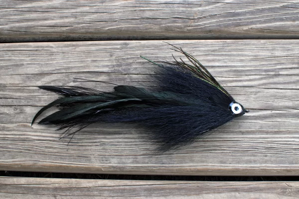 Urban Fly Co. Single Black Minnow fishing lure with a detailed eye, displayed on a wooden deck.