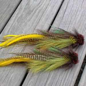 Urban Fly Co. Smallmouth Double Buford fishing lures with a vibrant mix of yellow, brown, and green feathers, displayed on a wooden deck.