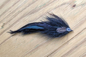 black minnow muskie fly in black on wood