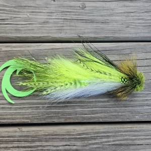 A fly fishing lure from Urban Fly Co. featuring vibrant feathers in shades of green and white, with a green tail, placed on a wooden surface.